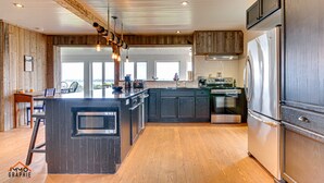 Une cuisine moderne avec des meubles en bois, un réfrigérateur en acier inoxydable et un grand îlot central doté d’un four encastré.