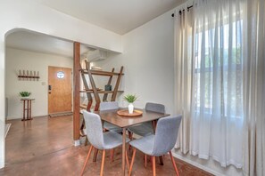 A dining area with a wooden table, grey upholstered chairs, and a white vase with plants. - ZonaMod MidCentury ⁜King ⁜FirePit ⁜Backyard ⁜Dog Friendly ⁜Near Downtown (Tucson)