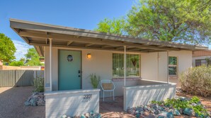 A single-story house with a covered porch, a door with a number, and a small seating area. - ZonaMod MidCentury ⁜King ⁜FirePit ⁜Backyard ⁜Dog Friendly ⁜Near Downtown (Tucson)