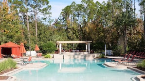 A swimming pool with a pavilion, lounge chairs, and a covered seating area. - Premium Villa at Champions Gate (Davenport)