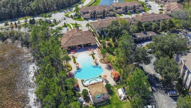An aerial view of a residential area with houses, a swimming pool, and a road. - Premium Villa at Champions Gate (Davenport)