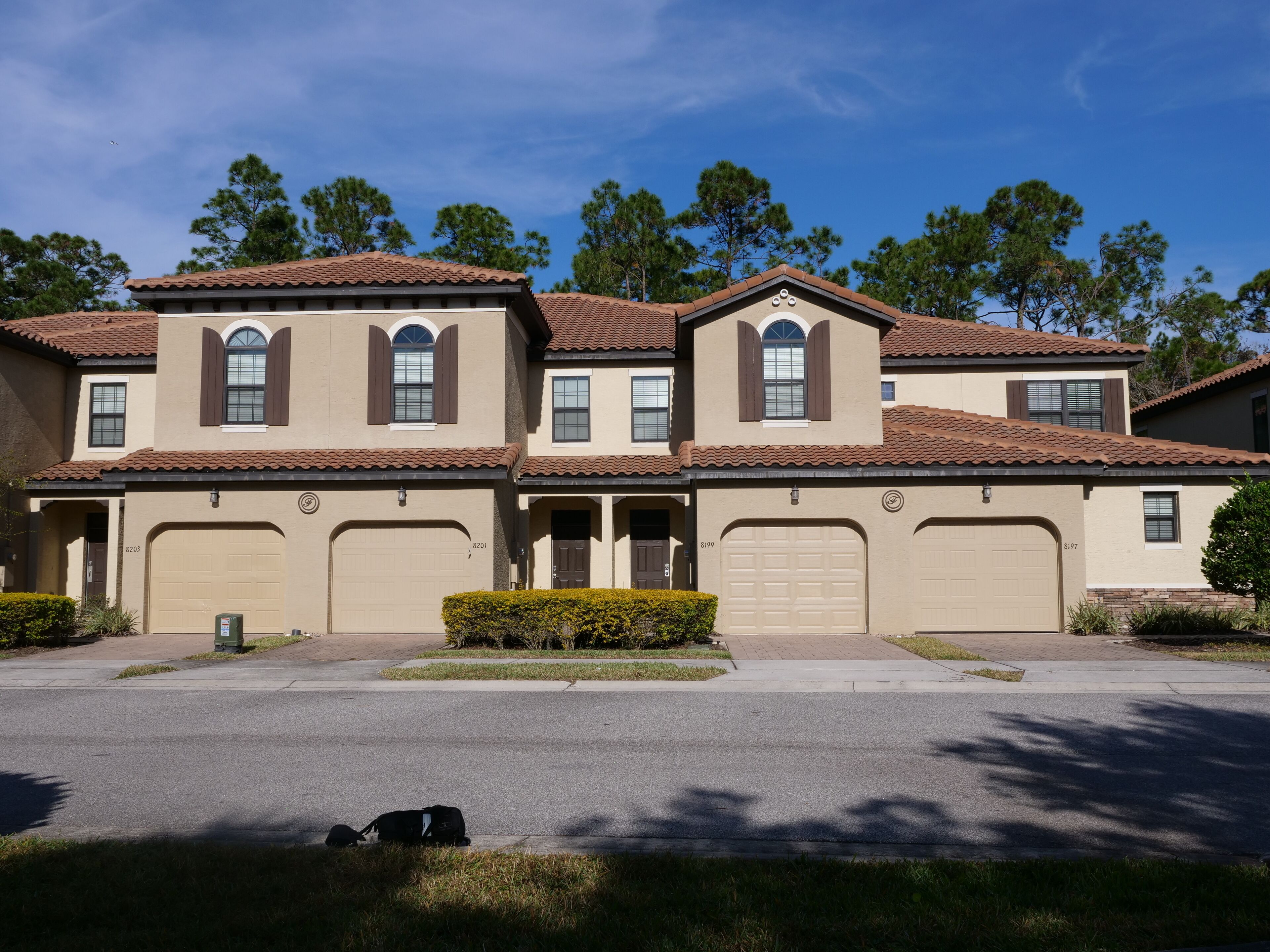 A two-story residential building with a symmetrical facade, multiple garage doors, and a well-maintained lawn.