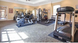 A gym with various exercise equipment, a Landice treadmill, and a ceiling fan. - Premium Villa at Champions Gate (Davenport)