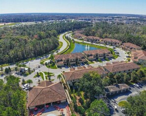 Townhouses surround a curved road, nestled among lush greenery and a serene body of water.