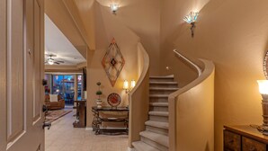 A spacious living area with a curved staircase, a dining area with a chandelier, and a view of the outdoors. - Golf & Mt VIEWS, Golfers/Hikers Paradise, Comm Htd Salt POOL & Spa, All King Beds (Gold Canyon)