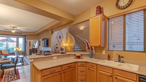 A modern kitchen with wooden cabinets, a double sink, and a staircase leading to another level. - Golf & Mt VIEWS, Golfers/Hikers Paradise, Comm Htd Salt POOL & Spa, All King Beds (Gold Canyon)