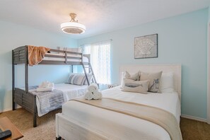 A bedroom with a bunk bed, a large bed, and a ceiling fan.