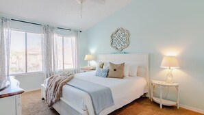 A bedroom with a bed, two bedside tables with lamps, a ceiling fan, and a decorative wall piece. - Beach Daze Sleeps 6 @ Gulf Highlands Dog Friendly (Panama City Beach)