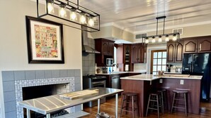 A modern kitchen with a central island, wooden cabinets, a built-in microwave, and a hanging light fixture.