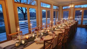 A long dining table set for a meal with candles, plates, and glasses.