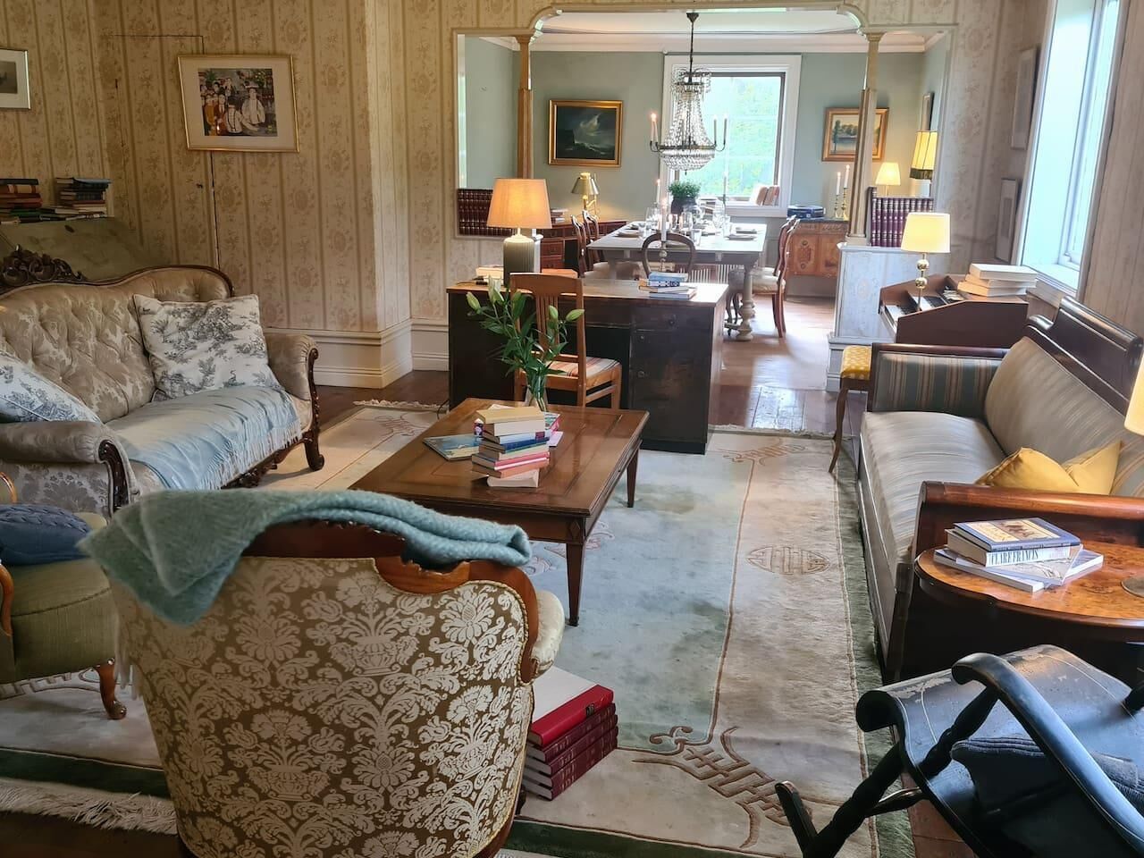 A spacious living room with a large sofa, a coffee table, and a dining area with a chandelier.