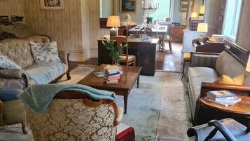 Un salon spacieux avec un grand canapé, une table basse et un coin repas agrémenté d’un lustre.