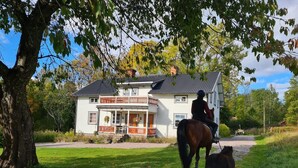 Une maison avec un porche et une personne à cheval.