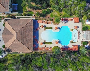 An aerial view of a resort with a central swimming pool, surrounded by lounge areas and vegetation. - Beautiful Villa in Champions Gate (Davenport)