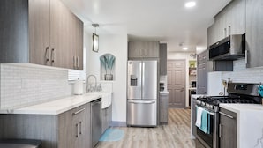 A modern kitchen with stainless steel appliances, wooden cabinets, and a tiled backsplash.