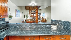 A kitchen with granite countertops, wooden cabinets, and a built-in microwave. - KAMAOLE SANDS 7402, REMODELED, AC, PARTIAL OCEAN, KAMAOLE BEACH PARK! (Kihei)