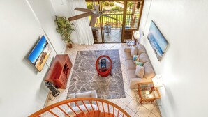 A spacious living area with a sofa, coffee table, and a view of the outdoors through a sliding glass door. - KAMAOLE SANDS 7402, REMODELED, AC, PARTIAL OCEAN, KAMAOLE BEACH PARK! (Kihei)