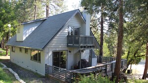 Une cabane à deux étages avec un balcon, entourée d’arbres.