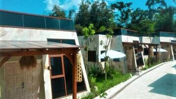A modern hotel with a covered outdoor seating area, a pool, and a garden.