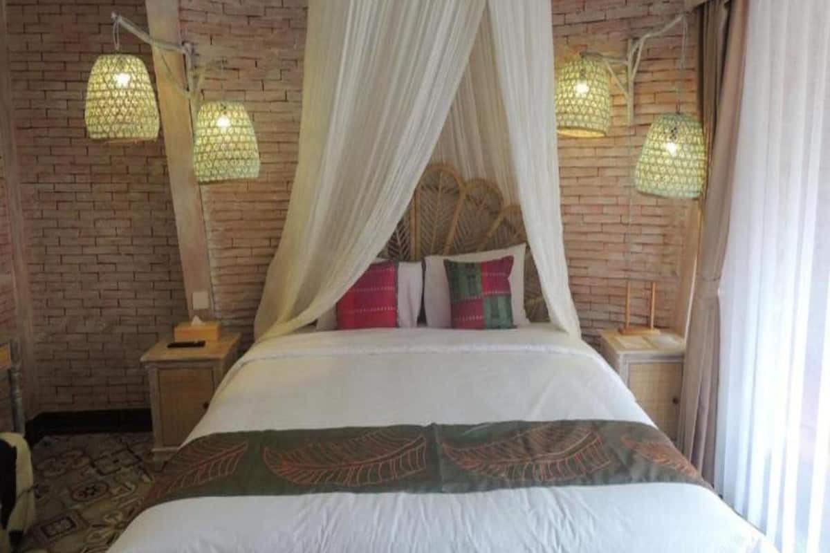Una cama con dosel, dos lámparas de noche y una pared de ladrillo.