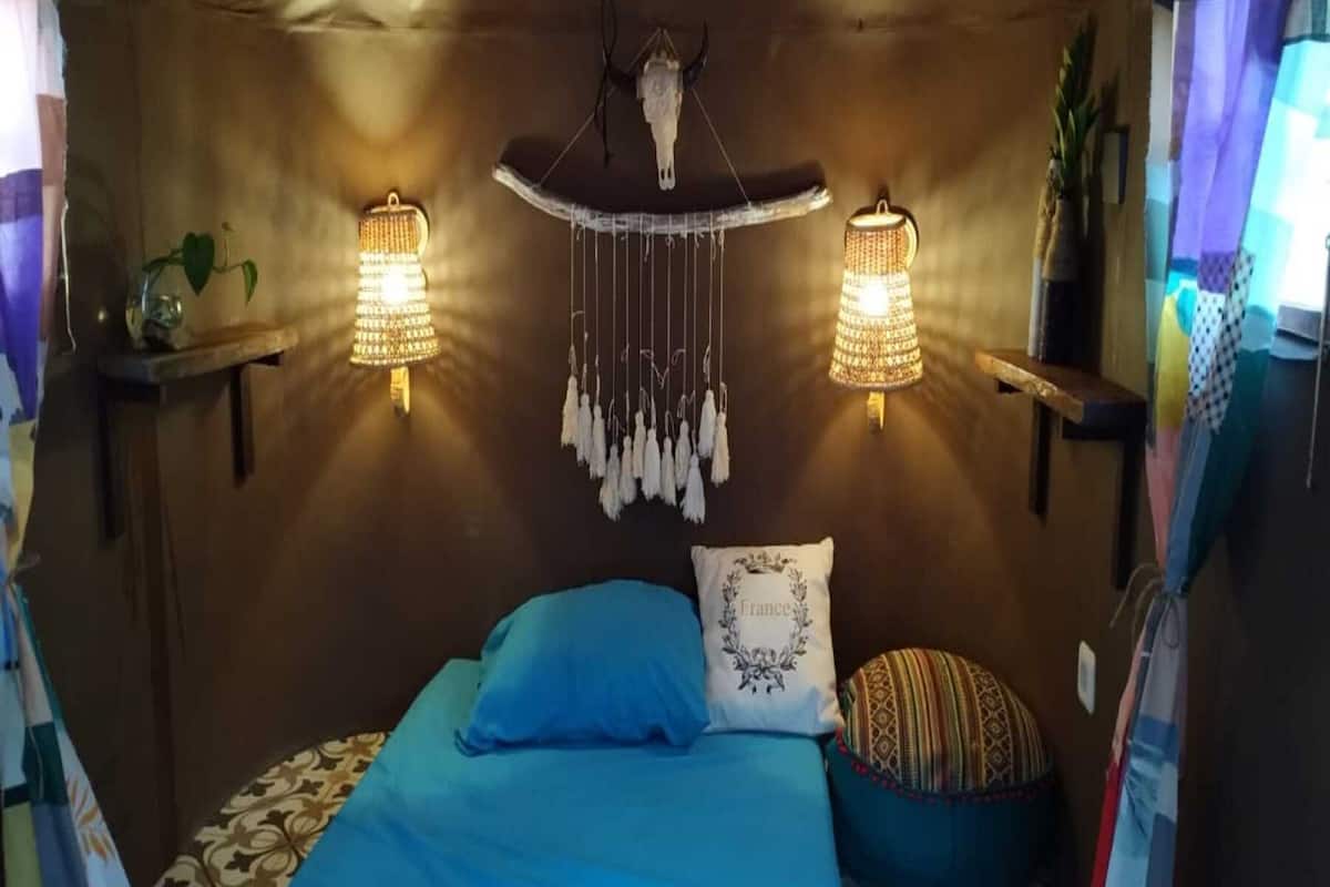 Una habitación acogedora con una cama, dos lámparas de pared y un colgador de luz.