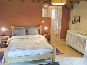 Une chambre à coucher avec un lit, des lampes de chevet, un berceau et un miroir.