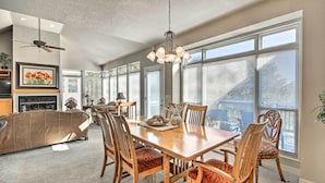 A spacious dining area with a wooden table and chairs, large windows, and a ceiling fan. - Bella Views! Biking/Walking Trail System Hub! (Bella Vista)