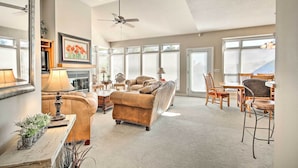A spacious living room with a large sofa, a dining area, and a ceiling fan. - Bella Views! Biking/Walking Trail System Hub! (Bella Vista)