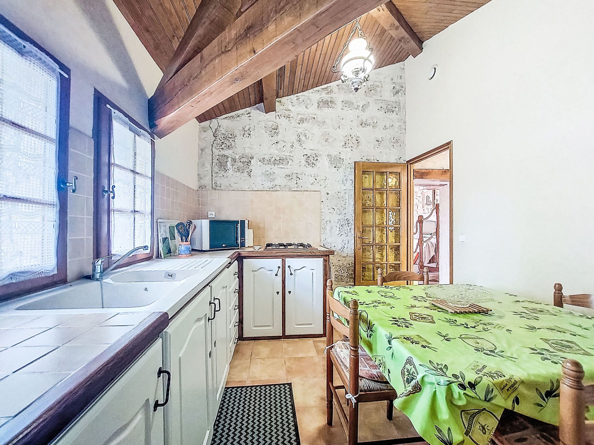 A compact kitchen with a sink, cabinets, a microwave, and a dining area with a table and chairs.