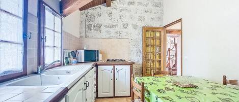 A compact kitchen with a sink, cabinets, a microwave, and a dining area with a table and chairs.