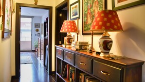 Un pasillo con un aparador de madera, libros, objetos decorativos e imágenes enmarcadas en la pared.