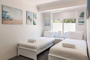 Ein Hotelzimmer mit zwei Betten, einem großen Fenster und Kunstwerken an den Wänden.