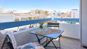 Un balcón con una mesa lista para dos personas, una silla y vistas de la ciudad.