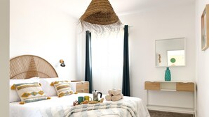 Un dormitorio con cama, mesita de noche, lámpara y espejo.