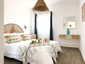 Un dormitorio con cama, mesita de noche, lámpara y espejo.