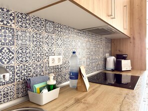 Una cocina con baldosas estampadas, dispensador de agua, porta pañuelos de papel y cafetera.