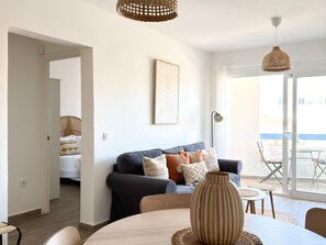 Una sala moderna con sofá, mesa de comedor y un amplio ventanal.