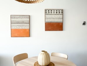 Un comedor con una mesa redonda, dos sillas y un jarrón.