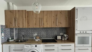 Eine moderne Küche mit Holzschränken, einer eingebauten Waschmaschine, einem Spülbecken und einem Backofen.
