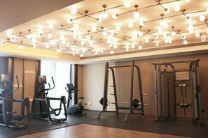 Un gimnasio con equipo de ejercicio, una barra de dominadas y un techo con luces colgantes.