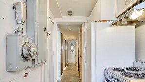 A narrow hallway with a kitchen area on the right, featuring a stove and a built-in oven. - 2 Mi to Dtwn: Boston Apartment Near Beaches! (Boston)