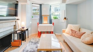 A modern living room with a sofa, a coffee table, a TV, and a dining table with chairs. - 2 Mi to Dtwn: Boston Apartment Near Beaches! (Boston)