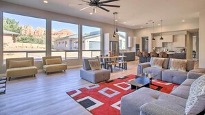 A spacious living room with a large window, a ceiling fan, and a dining area with a kitchen in the background. - Sedona Sanctuary w/ Hot Tub, Fire Pit & Grill (Sedona)