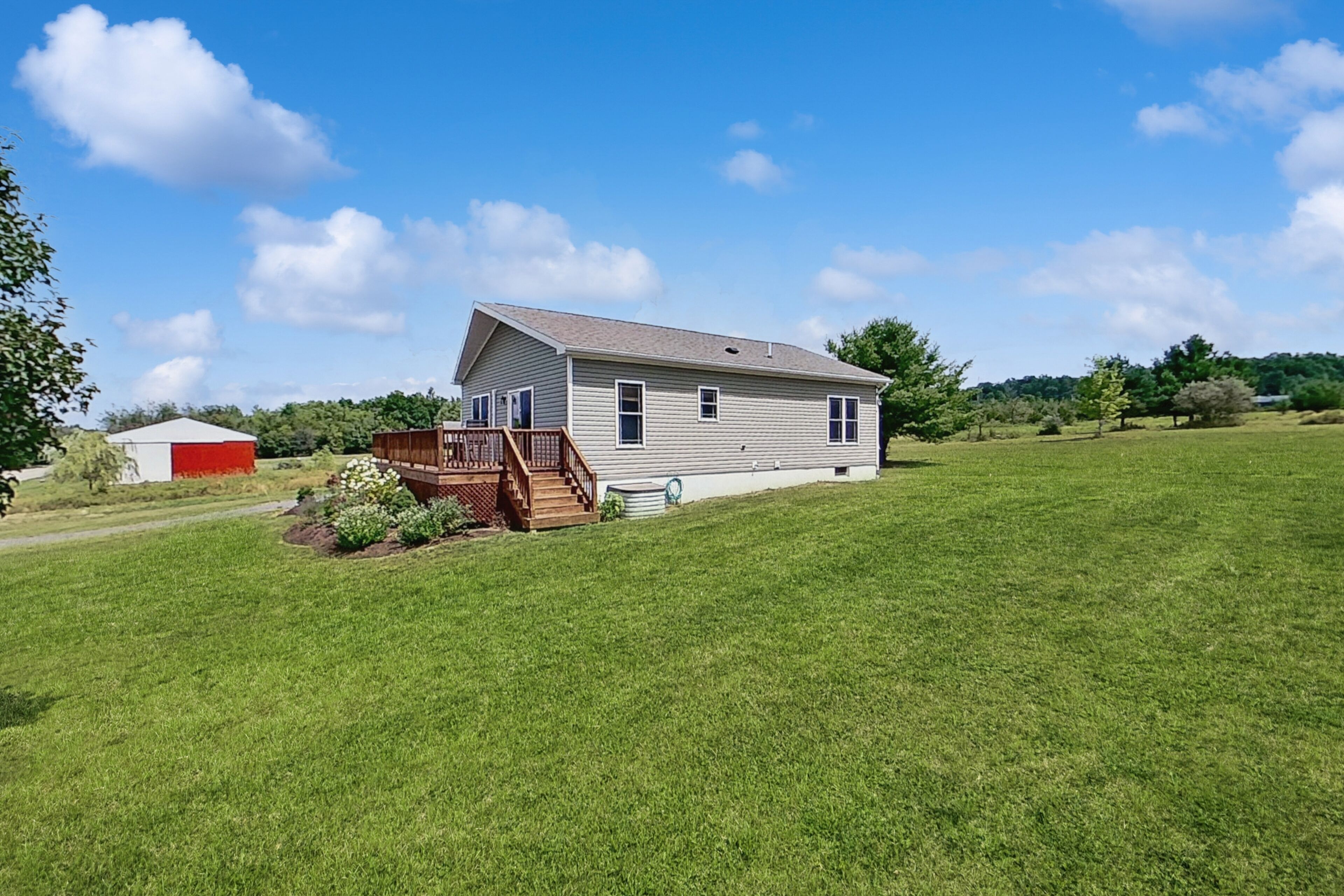 A single-story house with a front deck, a small garden, and a clear sky.