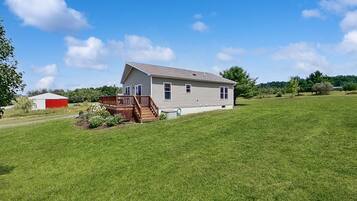A single-story house with a front deck, a small garden, and a clear sky.