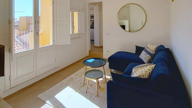A living room with a blue sofa, a round mirror, and a small table. - Appartamento Coturnia: A characteristic and welcoming apartment in the heart of the fascinating island of Ortigia, with Free WI-FI. (Siracusa)