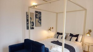 A bedroom with a four-poster bed, a blue sofa, and two wall-mounted lamps. - Appartamento Coturnia: A characteristic and welcoming apartment in the heart of the fascinating island of Ortigia, with Free WI-FI. (Siracusa)
