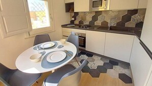 A compact kitchen with a microwave, stove, and a dining area with a table and chairs. - Appartamento Coturnia: A characteristic and welcoming apartment in the heart of the fascinating island of Ortigia, with Free WI-FI. (Siracusa)