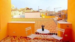 A balcony with a tiled roof, a white table, and two white chairs. - Appartamento Coturnia: A characteristic and welcoming apartment in the heart of the fascinating island of Ortigia, with Free WI-FI. (Siracusa)