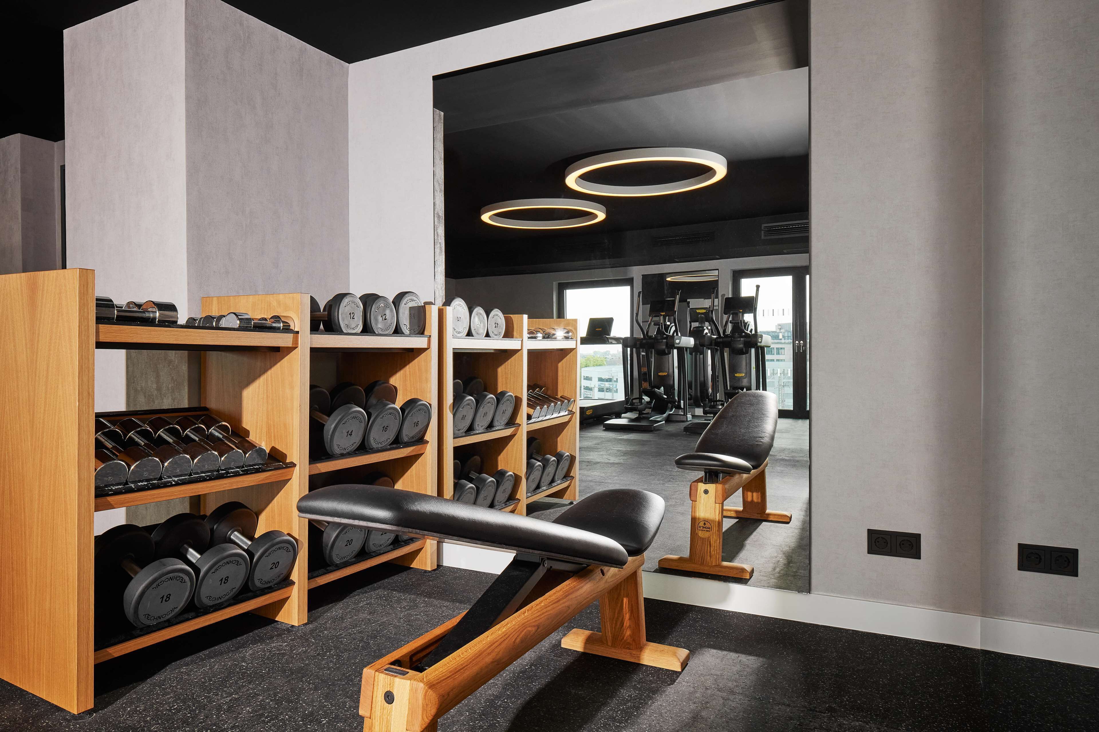 Un gimnasio con estantes de madera que sostienen mancuernas, un banco y equipo de ejercicio.